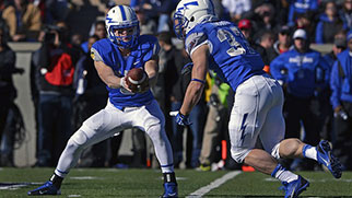 A football player hands the ball off to another player